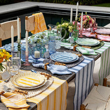 Colorful cabana melamine plates and linens set up at a table poolside 